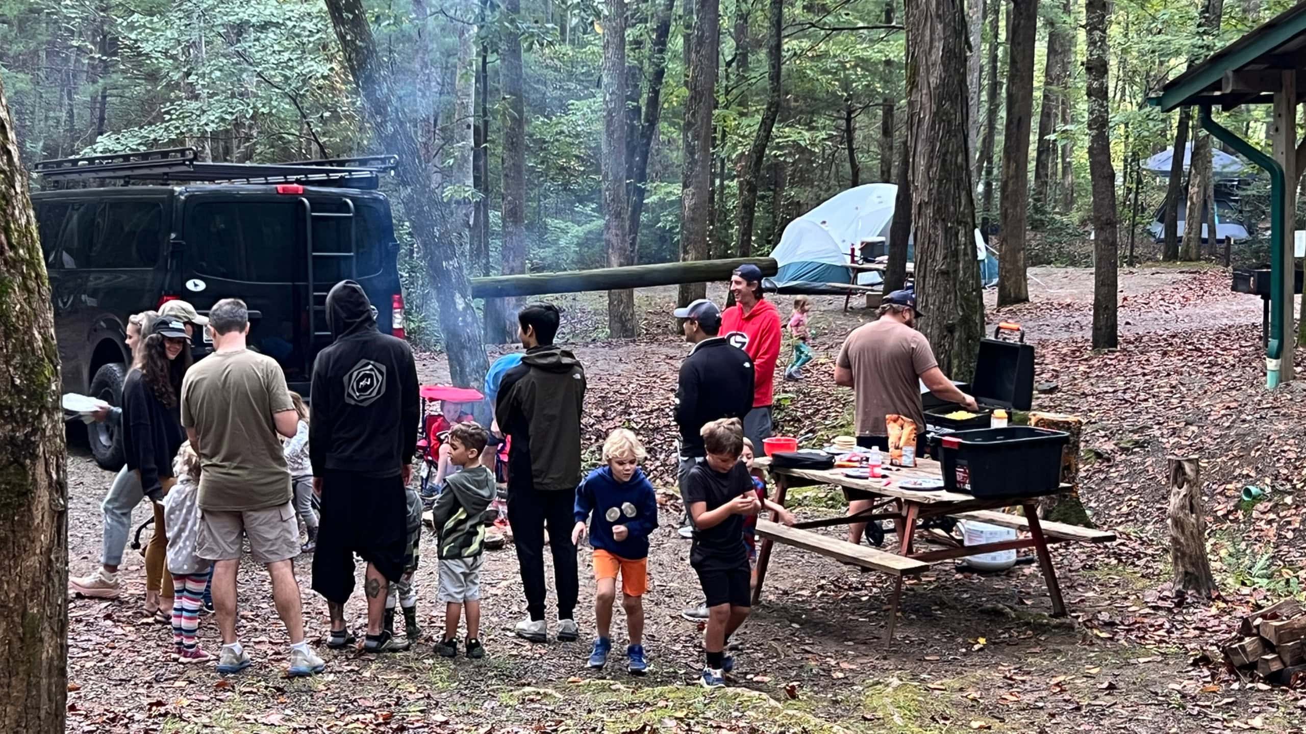 Outdoor troop gathering around a campfire in the woods.